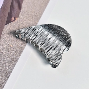 Detail shot of heart-shaped silver hair claw clip with brushed metal texture