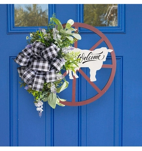Detail of a rustic cow wheel wreath with Welcome sign on a blue front door decor