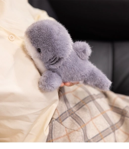 Détail d'un requin en peluche gris et blanc tenu pour montrer sa texture douce et soyeuse