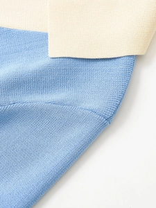 Close-up of knit fabric detail showing blue and cream contrast stitching and fine texture