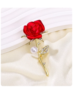 Detail of elegant red rose brooch with gold finish, sparkling rhinestones and a pearl