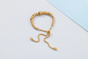 Detail of adjustable gold beaded bracelet with box chain and polished sliding toggle