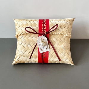 Detail of handmade bamboo gift box with red silk ribbon and elegant pearl pendant charm