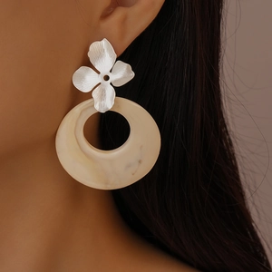 Close-up of resin marble hoop earrings with silver floral detail worn by model