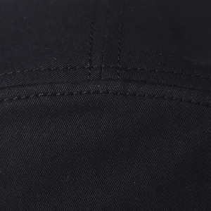 Close-up of double-stitch sewing details on a black cotton twill baseball cap fabric