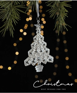 Sparkling clear acrylic Christmas tree ornament hanging on green pine branch with golden bokeh