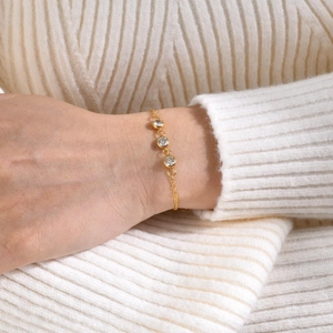 Gold stainless steel chain bracelet featuring three green zircon stones on model wrist