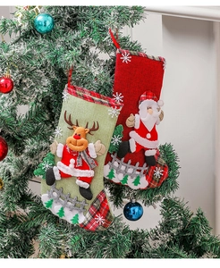 Gros plan de chaussettes de Noël en toile de jute avec Père Noël et renne sur sapin