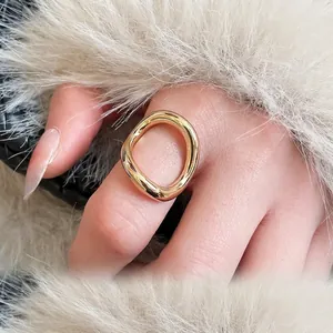 Minimalist golden geometric open ring with irregular liquid metal texture on white plush