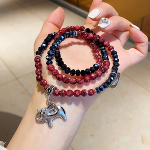 Detail of multi-layer beaded bracelet featuring silver elephant and heart charms on wrist