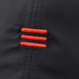 Dettaglio macro del tessuto ripstop esagonale nero con tripla striscia ricamata rossa