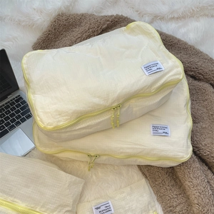 Detailed view of beige grid travel organizer bags with yellow zippers on a cozy blanket