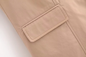Close-up of khaki sleeveless blazer pocket flap with high-density woven fabric and stitching