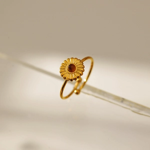Detail of a gold flower ring featuring a brown gemstone and adjustable open band