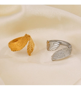 Detailed close-up of gold and silver feather wing rings on a smooth yellow silk fabric