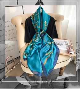 Detail of teal silk scarf with almond blossom print draped over a black dress