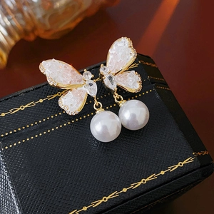 Detail of gold butterfly earrings with pink crystals and hanging white pearls