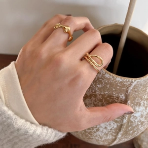Close-up of minimalist gold-plated wave and triple cross ring set on fingers