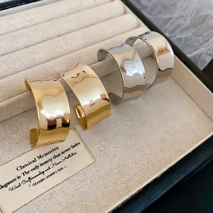 Minimalistische breite Wellenringe in Gold und Silber auf beige Samt präsentiert