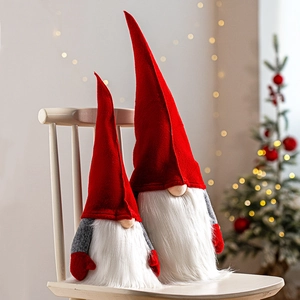 Plush Christmas gnomes in red and grey sitting on a white chair with warm festive lights