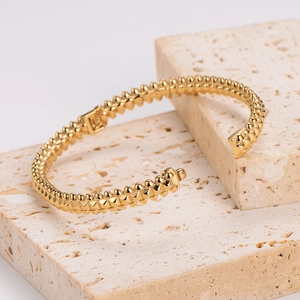 Macro detail of gold-plated stainless steel rivet cuff with structural clasp design