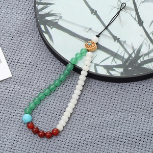 Detail of beaded phone wrist strap with white jade and turquoise on gray fabric background