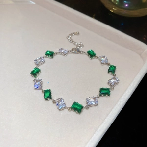 Detailed close-up of adjustable silver bracelet with green and clear rectangular crystals
