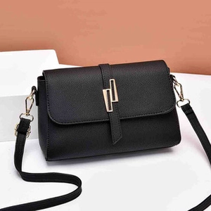 Detail of black pebbled leather texture with geometric gold buckle on shoulder bag