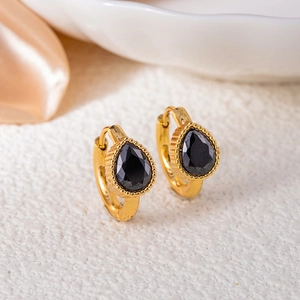 Detailed close-up of vintage gold-plated earrings with black teardrop gemstone settings