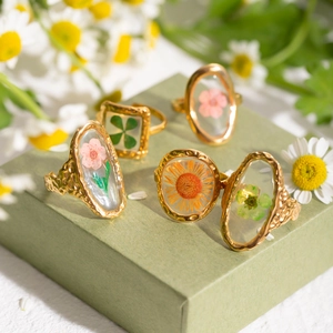Golden stainless steel sunflower rings with real dried flowers in a green display box