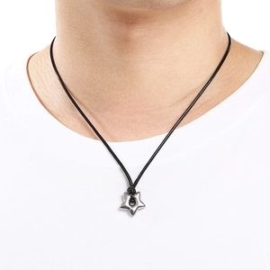 Close-up of a silver hollow star pendant on a black cord necklace worn on a white shirt