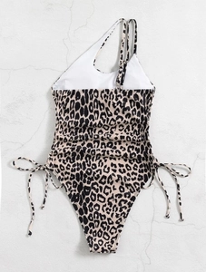 Detail of leopard print swimsuit featuring asymmetrical straps and side drawstring ties