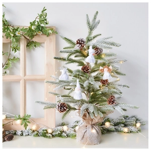 Close-up of small flocked Christmas tree with angel ornament, pine cones and LED lights