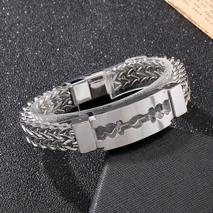 Detailed close-up of a silver men's stainless steel bracelet with a razor blade motif