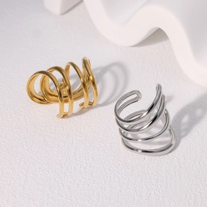Minimalist spiral ear cuffs in gold and silver finish on a textured white background