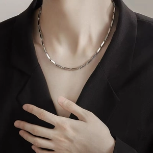 Collier minimaliste en acier titane argenté sur un mannequin masculin portant un costume noir
