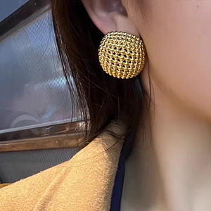 Elegante goldene Hohlkugel-Ohrstecker mit Wabenstruktur an einem weiblichen Modell