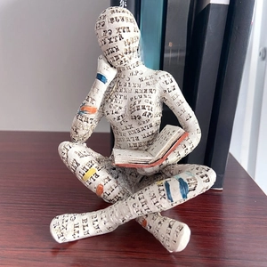 Detail of artistic Reading Woman figurine with vintage newspaper texture and color accents