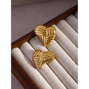 Close-up of 18k gold heart earrings with woven texture on white velvet jewelry box