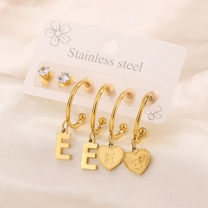 Dettaglio del set di orecchini in acciaio placcato oro 18k con cuore e lettera E su seta
