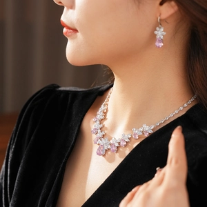 Gros plan d'un ensemble collier et boucles d'oreilles argenté avec cristaux roses