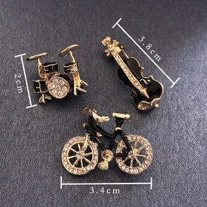 Detailed size view of alloy pins in drum, violin, and bicycle shapes with rhinestones