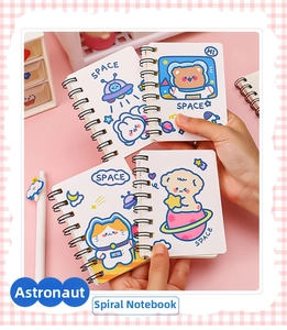 Close-up of a hand holding a cute A7 mini astronaut spiral notebook in a pink setting