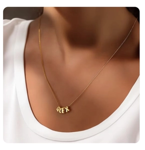 Detailed view of Alex letter pendant on a golden necklace worn by a model