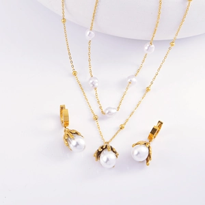 Flat lay of gold chain necklace and matching pearl earrings on a clean white background