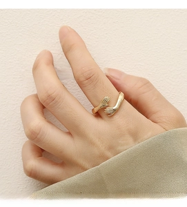 Close-up of golden hugging hands open ring on finger with high polish finish