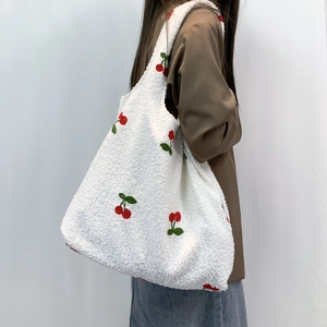 Close-up of white plush tote bag featuring detailed red and green cherry embroidery