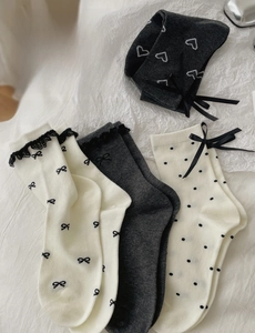 Detail of cream cotton socks featuring delicate lace edges and black satin bows