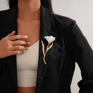 Elegant gold and white enamel flower brooch with wrinkled texture on a black blazer
