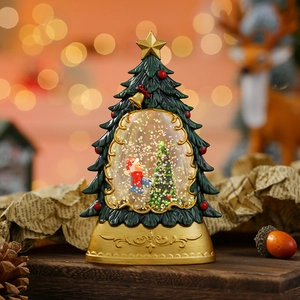 Detailed view of a Christmas tree snow globe with a gold base and festive scene
